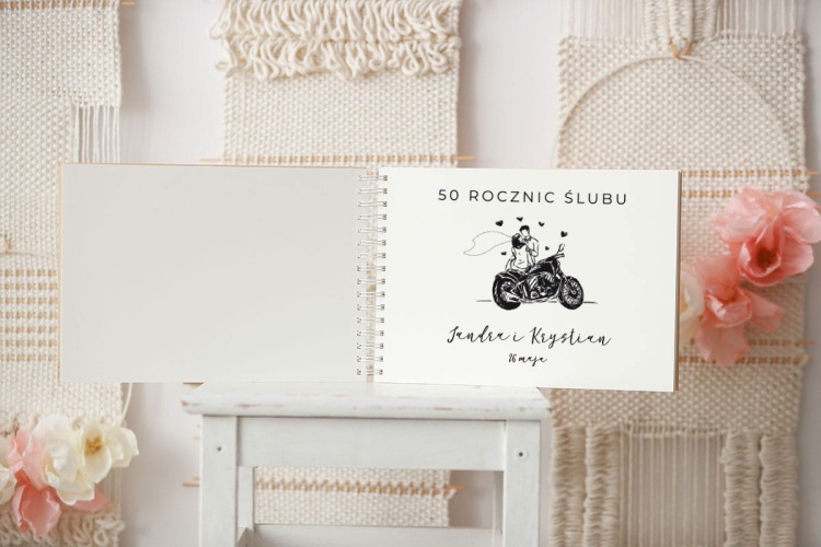 Pierwsza strona drewnianej kroniki z wygrawerowaną grafiką pary młodej na motorze