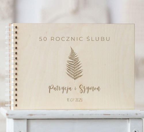 Drewniana okładka kroniki 50 rocznic z wygrawerowaną paprotką